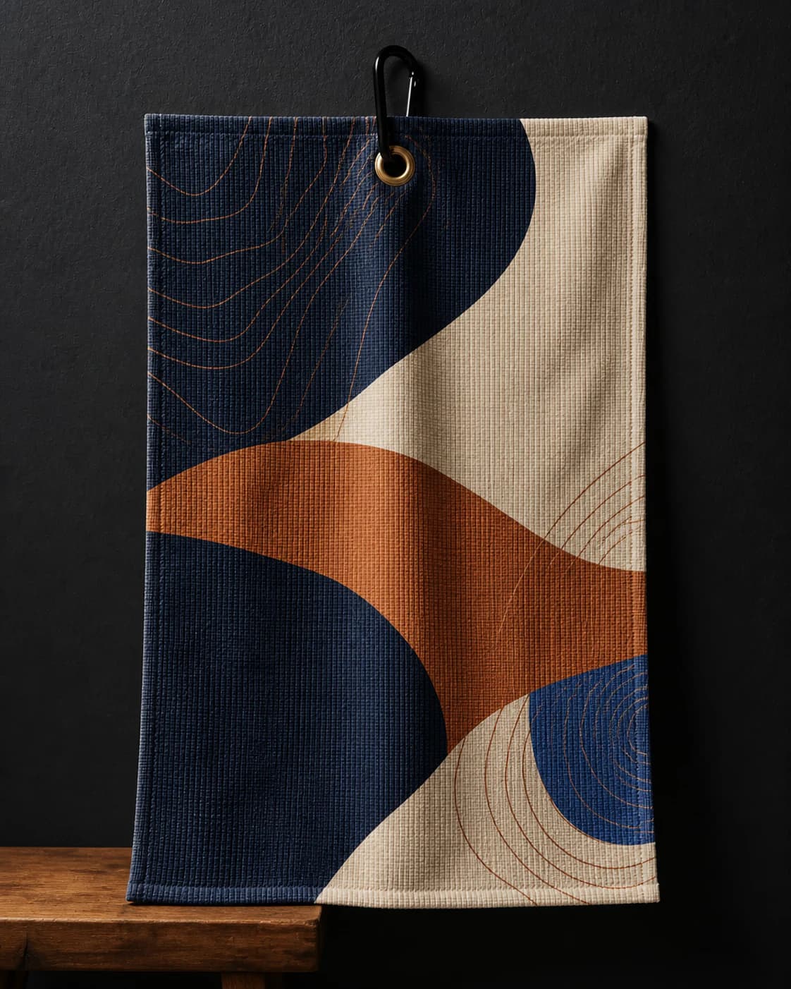 Custom golf towel with navy, ivory, and copper artwork hanging from a brass grommet